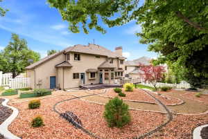 Spacious tiered backyard featuring decorative rock beds, mature landscaping, and a miniature railway track
