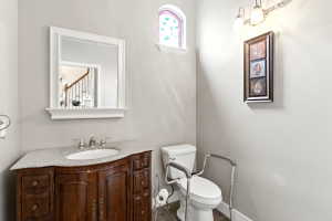 Powder room featuring a curved wood-finish vanity with an undermount sink, a light-colored countertop, and a white framed mirror