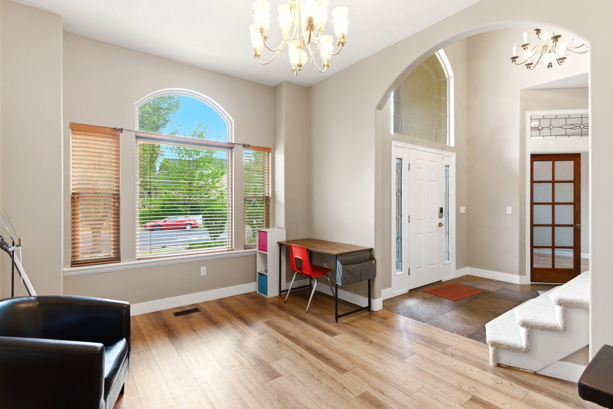 Entryway featuring a white paneled front door with decorative glass side panels and a transom window, a grand arched opening, and a chandelier