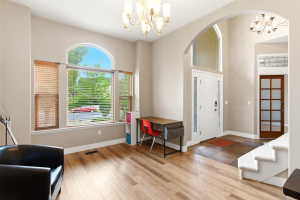 Entryway featuring a white paneled front door with decorative glass side panels and a transom window, a grand arched opening, and a chandelier