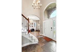 Grand entryway featuring a white paneled door with decorative sidelights and an arched transom window