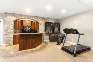 Built-in wet bar with stacked stone archway, wood cabinetry, and granite-look countertop