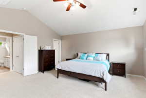 Spacious room featuring vaulted ceilings, light-colored carpeting, and a ceiling fan with integrated lighting