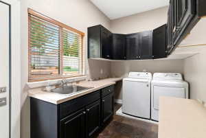 Laundry area featuring dark cabinetry, a utility sink, and a spacious countertop