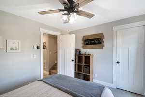 Light grey walls with white trim throughout, featuring a ceiling fan with wood-finish blades and integrated lighting