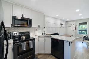 Modern kitchen featuring white shaker cabinetry, stainless steel appliances, a subway tile backsplash, and light wood-finish flooring