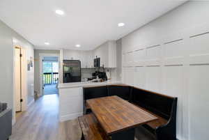 Modern kitchen area featuring light wood-finish flooring, recessed lighting, and a board and batten accent wall
