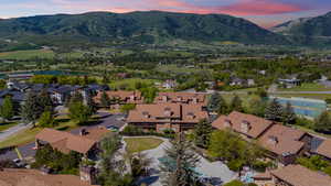 Aerial perspective showcasing a complex of buildings with brown shingle roofs and stone accents, surrounded by mature trees