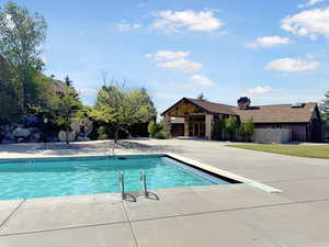 Outdoor swimming pool featuring concrete decking, integrated pool cover, and metal entry rails