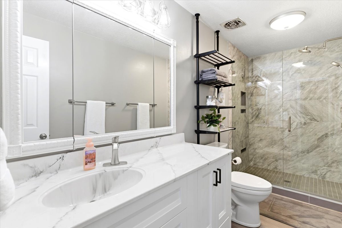 Bathroom featuring a white vanity with an undermount sink, a white countertop with grey veining, and a large mirrored medicine cabinet