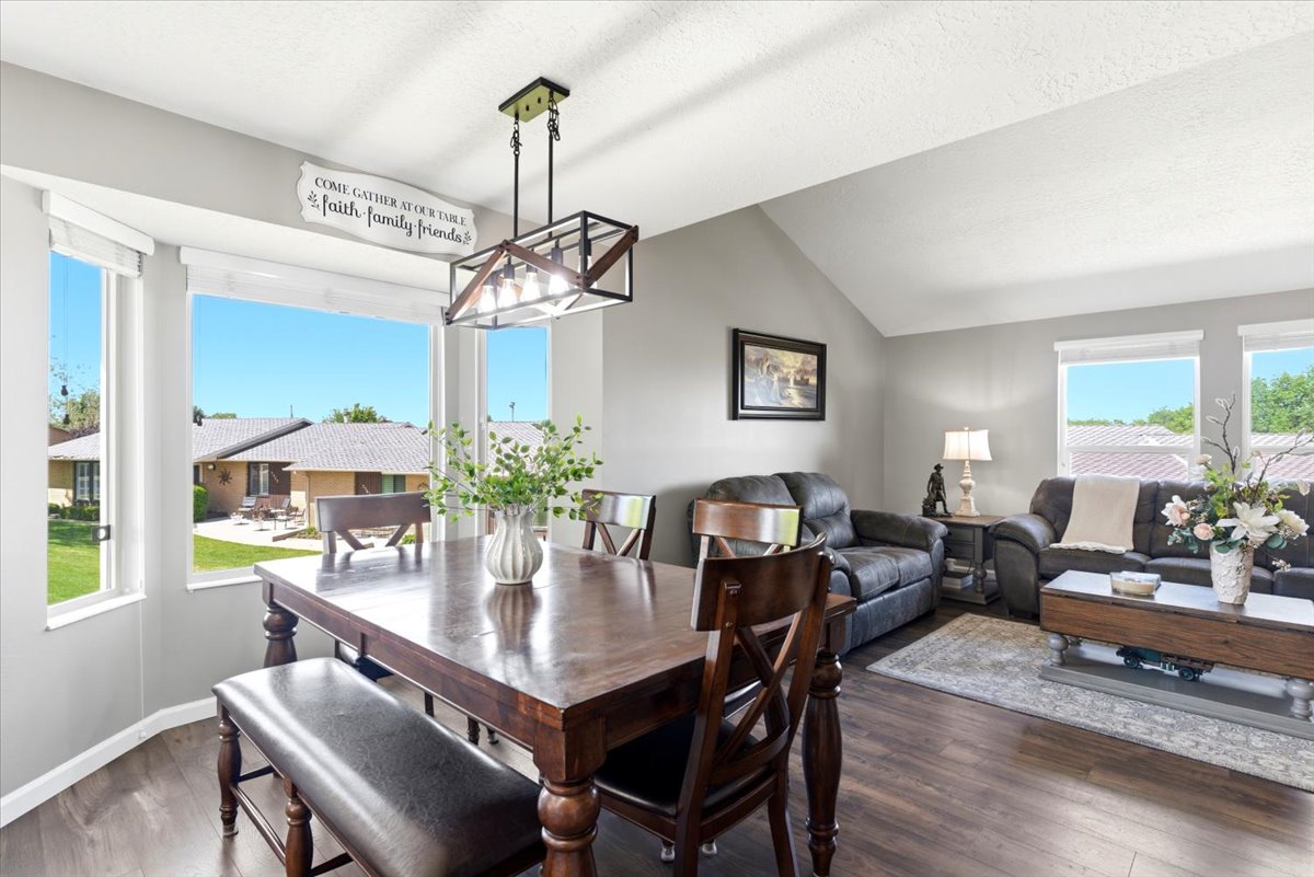 Open concept living space featuring a vaulted ceiling and wood-finish flooring