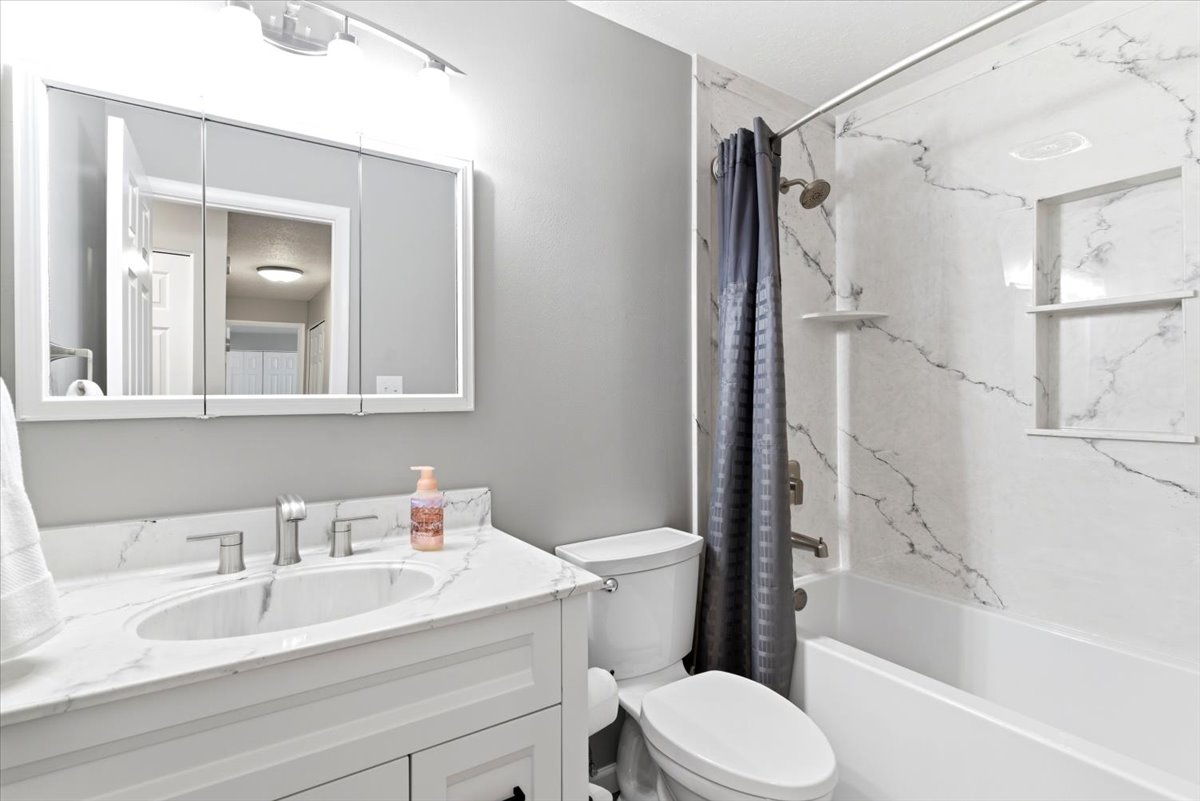 Bathroom featuring a white vanity with an integrated sink, brushed nickel faucet, and a large mirrored medicine cabinet