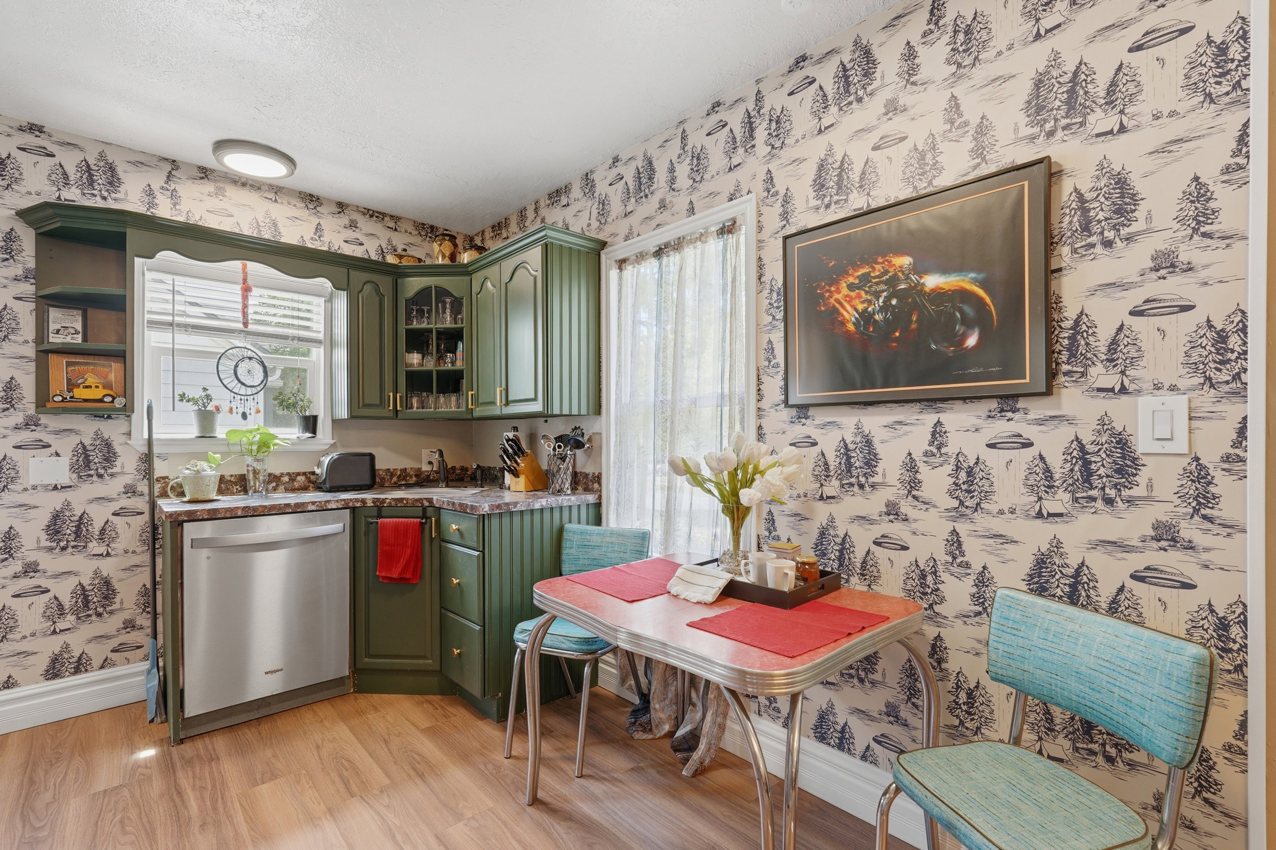 Kitchen featuring green cabinetry, a stainless steel dishwasher, and wood-finish flooring