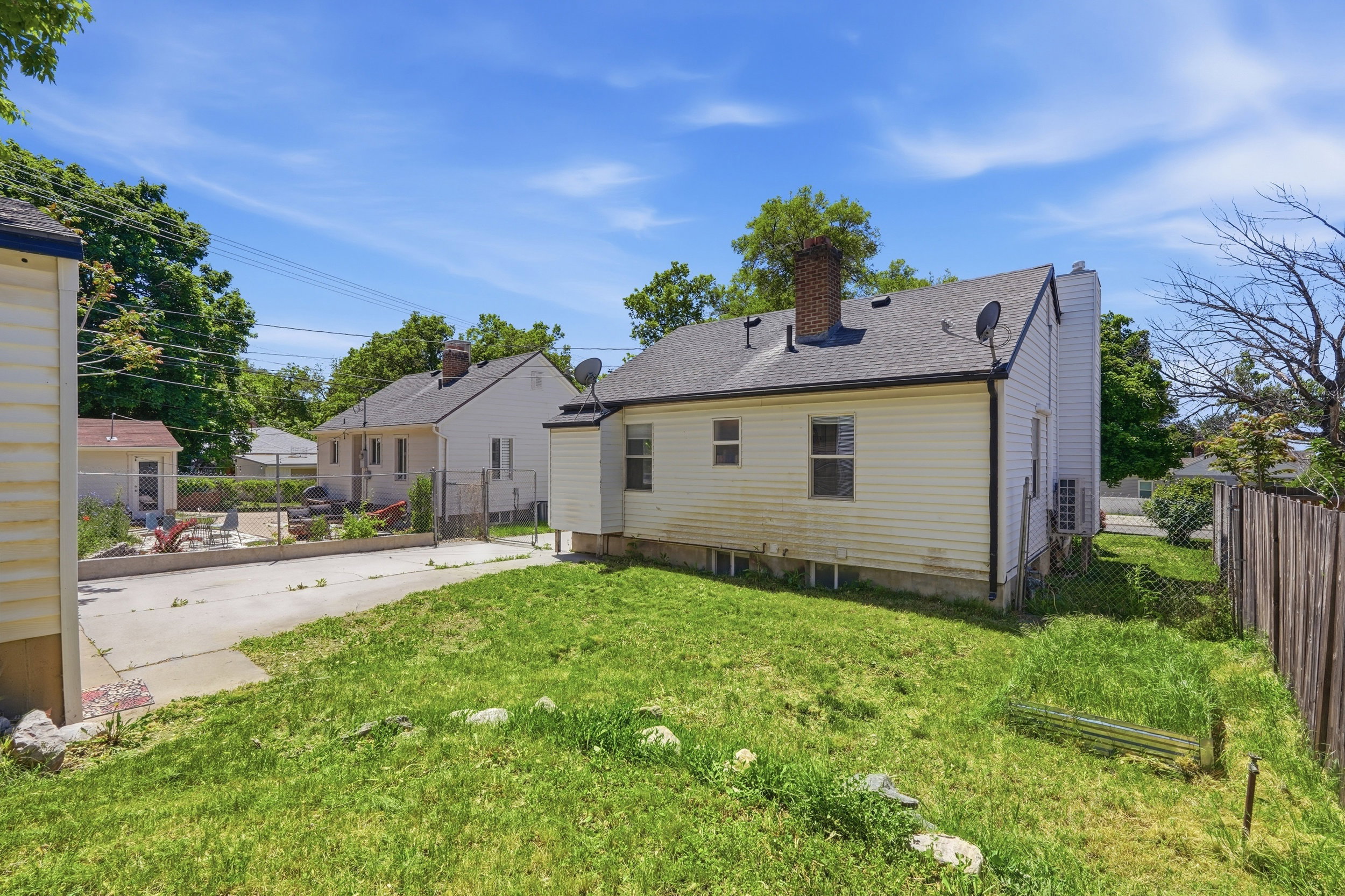 Spacious rear yard with a concrete patio, wood fence, and a detached shed