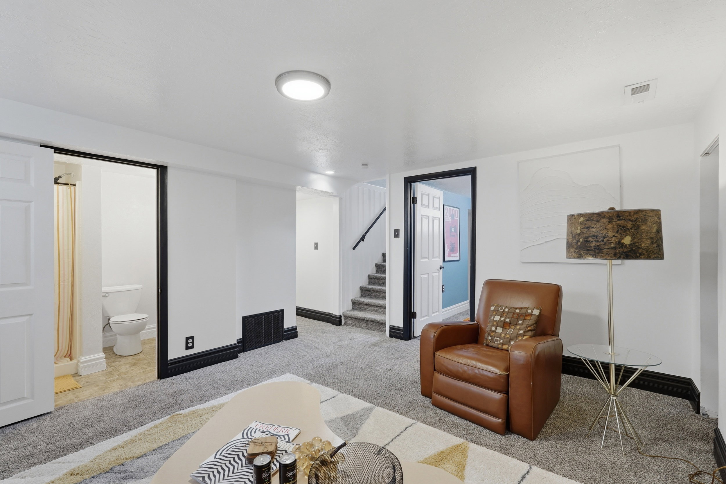 Living room featuring recessed lighting, a carpeted floor, a built-in staircase, and a visible bathroom off main.
