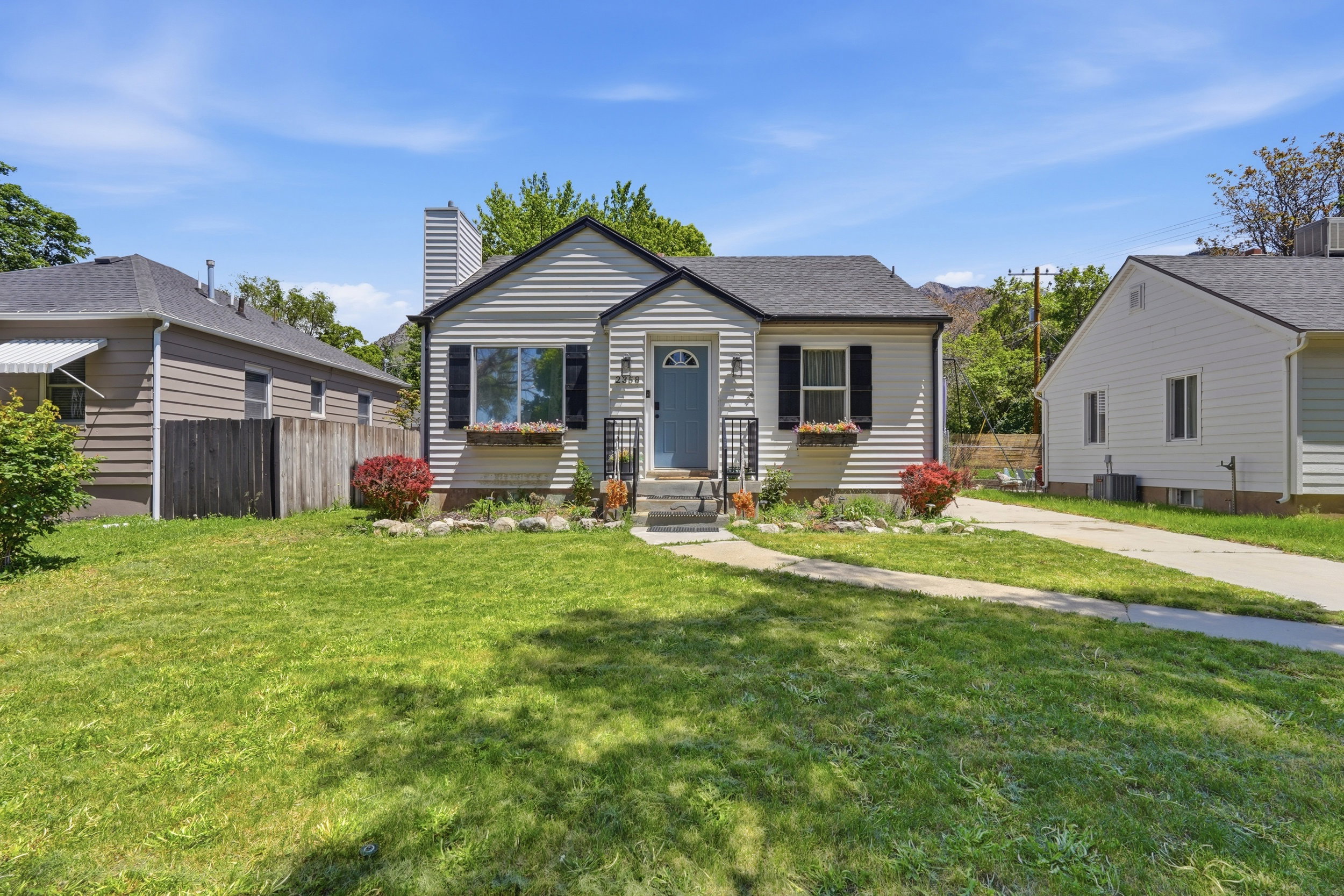 Traditional home with light-colored siding, black shutters, and a contrasting blue front door