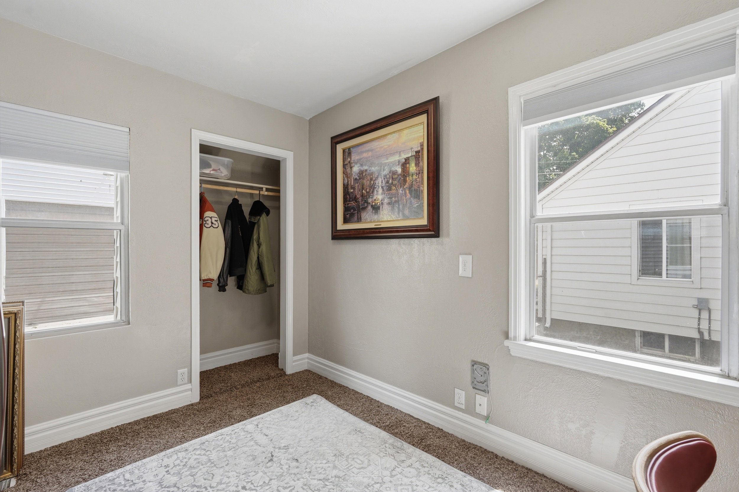Bedroom 2 featuring two windows with white trim, a closet with a hanging rod, and light-colored walls