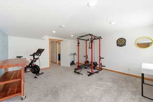 Spacious room featuring light gray carpeting, recessed ceiling lighting, and a neutral wall color with a light blue accent wall