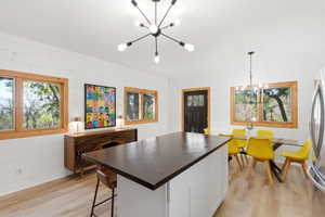 Open-concept living space featuring a central island with a dark countertop, light wood-finish flooring, and white shiplap walls