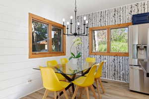 Dining area featuring wood-finish flooring, white shiplap wall, and a patterned accent wall