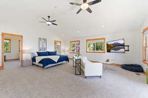 Spacious room featuring vaulted ceilings, light-colored carpeting, and multiple windows with wood trim