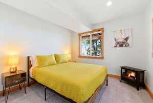Carpeted room featuring a window with wood trim, recessed lighting, and a built-in electric fireplace