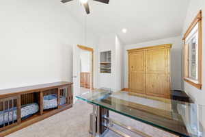 Vaulted ceiling room featuring light tan carpeting and a ceiling fan