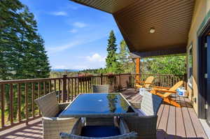 Spacious outdoor deck featuring wood-finish flooring, a full-height wood railing, and a slatted wood ceiling
