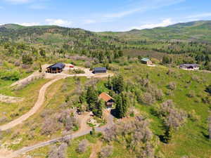 Spacious hillside property featuring multiple homes, expansive natural landscaping, and a mountainous backdrop