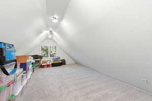 Carpeted attic space with sloped ceilings, recessed lighting, and a single window