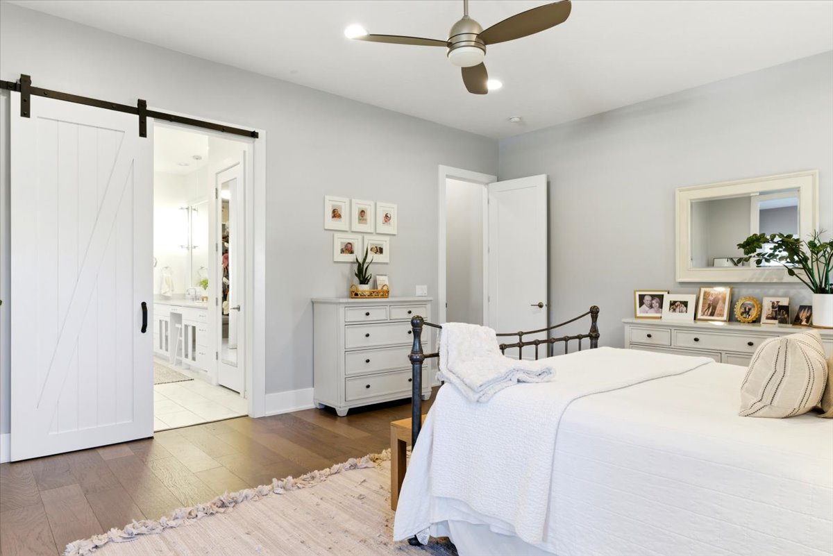 Spacious room featuring wood-finish flooring, a contemporary ceiling fan with integrated lighting, and light gray wall paint
