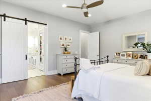 Spacious room featuring wood-finish flooring, a contemporary ceiling fan with integrated lighting, and light gray wall paint