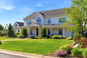 White siding exterior with a dark shingle roof, featuring a covered front porch, an arched entry, and a prominent gable