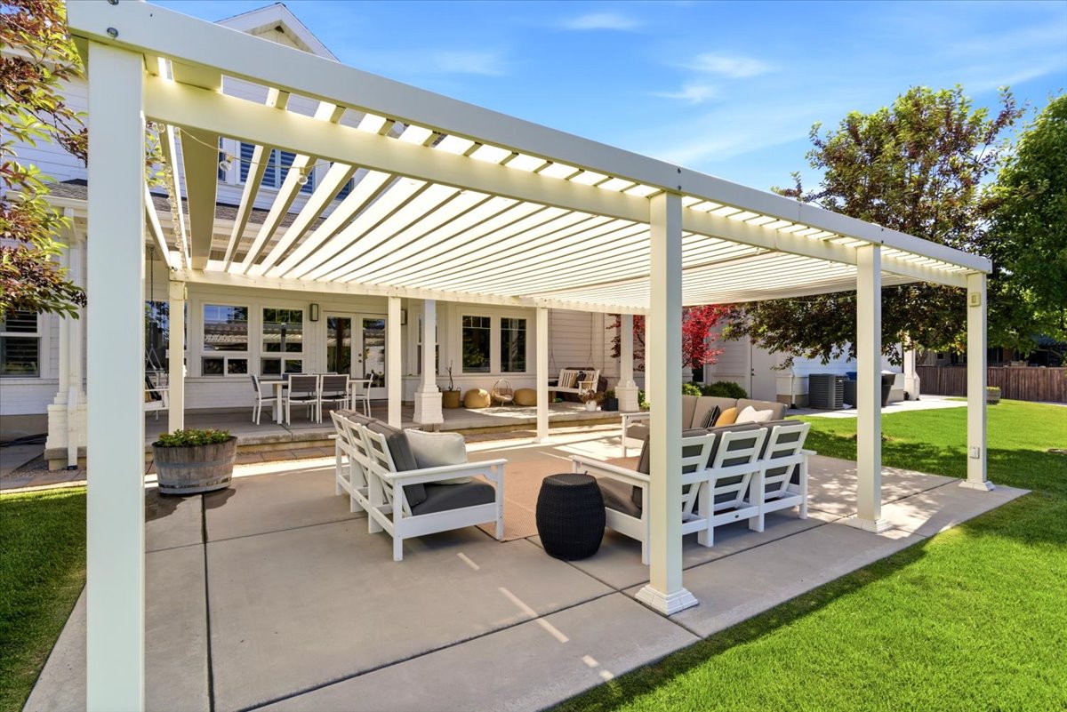 Expansive patio featuring a pergola, concrete surfacing, and direct access to the interior via multiple doors