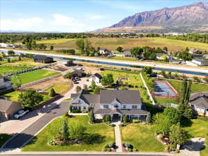 Expansive property featuring a large residence with a front porch, a separate, mature landscaping, and mountain scenery