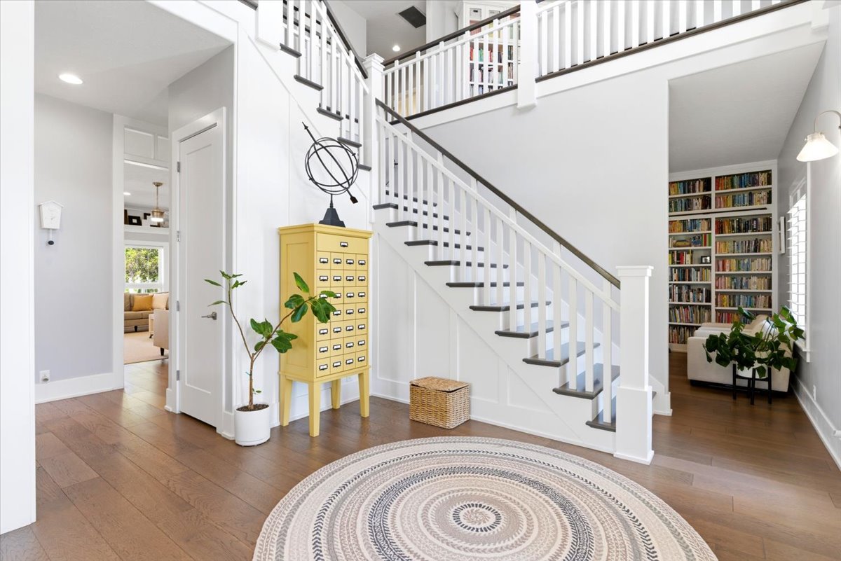 Grand entry foyer featuring wood-finish flooring and a multi-level staircase with white balusters and dark treads