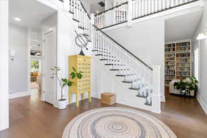 Grand entry foyer featuring wood-finish flooring and a multi-level staircase with white balusters and dark treads