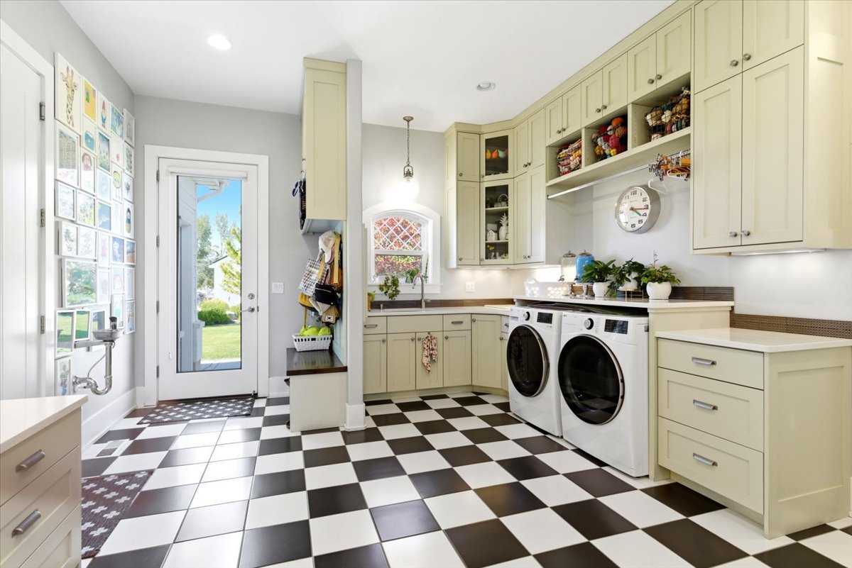 Utility room featuring checkerboard tile flooring, extensive cabinetry, a built-in bench with storage, a countertop workspace, and a glass-paneled exterior door