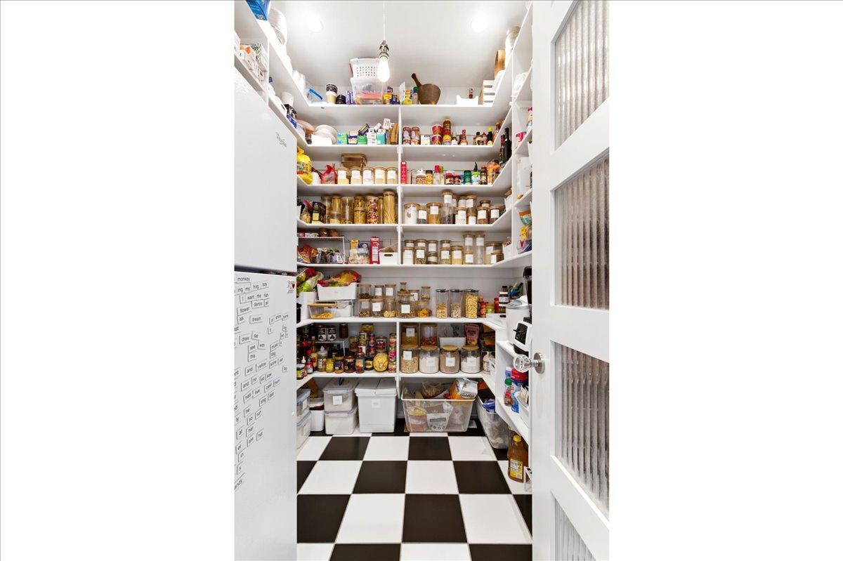 Pantry featuring extensive built-in shelving, checkered flooring