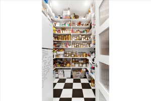Pantry featuring extensive built-in shelving, checkered flooring