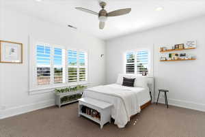 Bright interior room featuring a large window with white plantation shutters, recessed lighting, and a ceiling fan