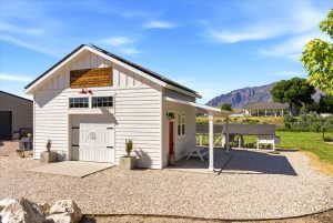 White siding outbuilding with a gabled roof and carriage-style doors