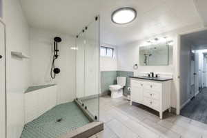 Bathroom featuring a glass-enclosed shower with matte black fixtures, white subway tile walls, and a light green hexagonal tile floor