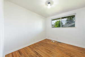 Hardwood flooring, white baseboards, and a single window offering natural light