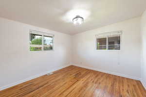 Room featuring wood-finish flooring, white baseboards, and bright white walls