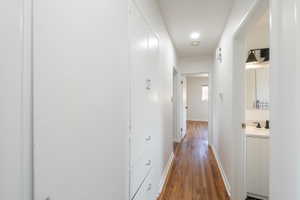 Hallway featuring wood-finish flooring, recessed lighting, and built-in white cabinetry with drawers