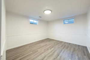 Spacious room featuring newer flooring, white walls with wainscoting