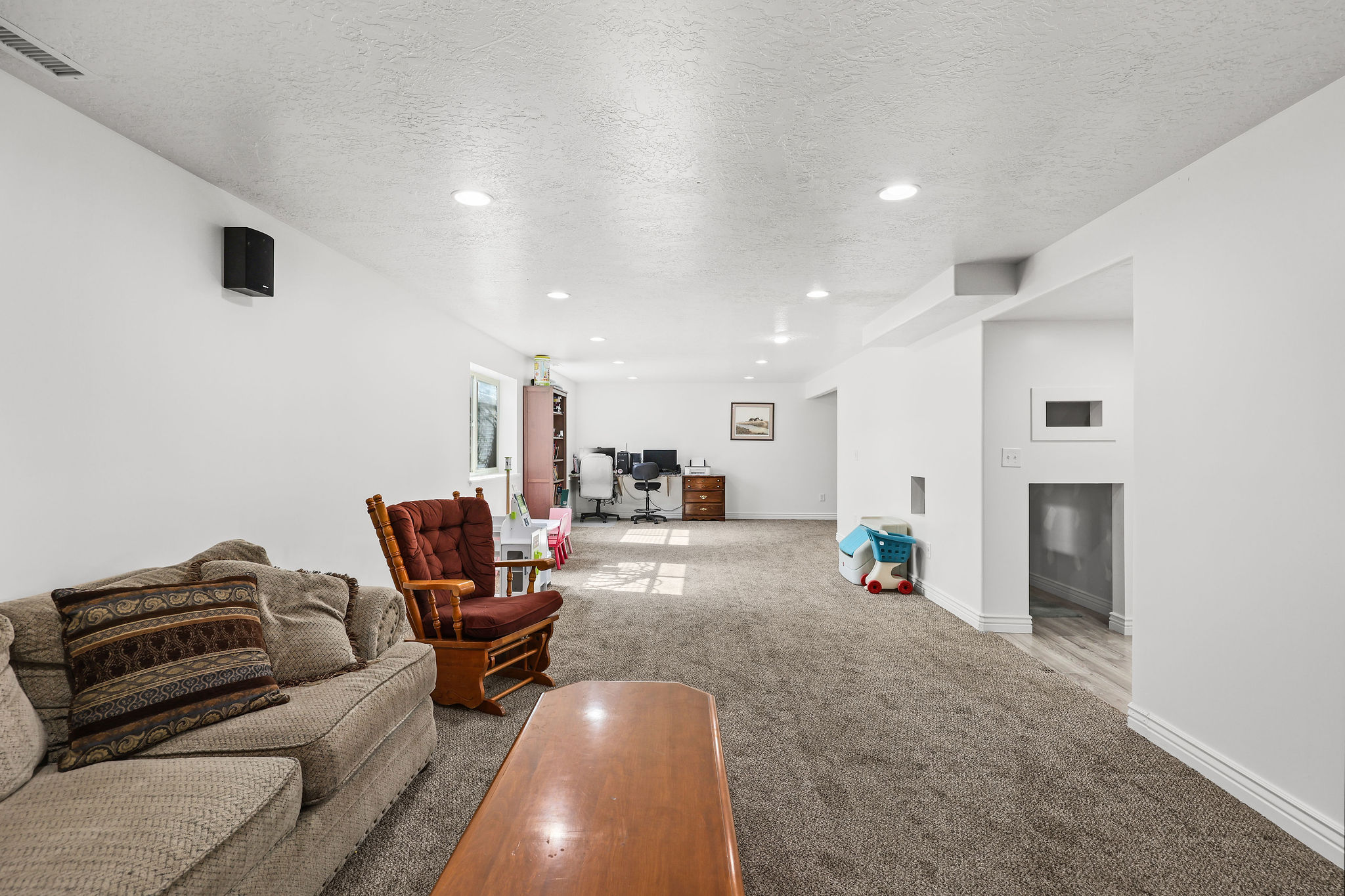 Spacious lower-level room featuring recessed lighting, light-toned carpeting, and white painted walls