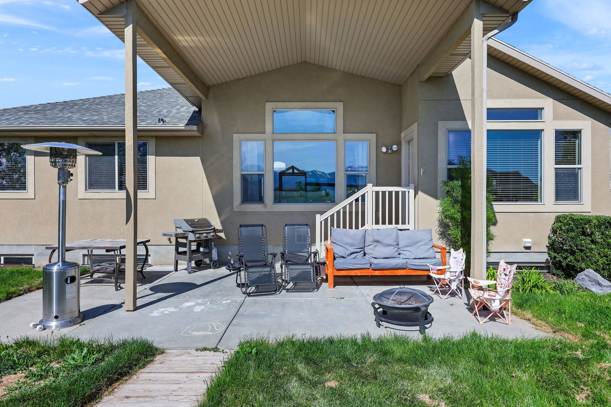 Covered concrete patio with stucco exterior and white railing