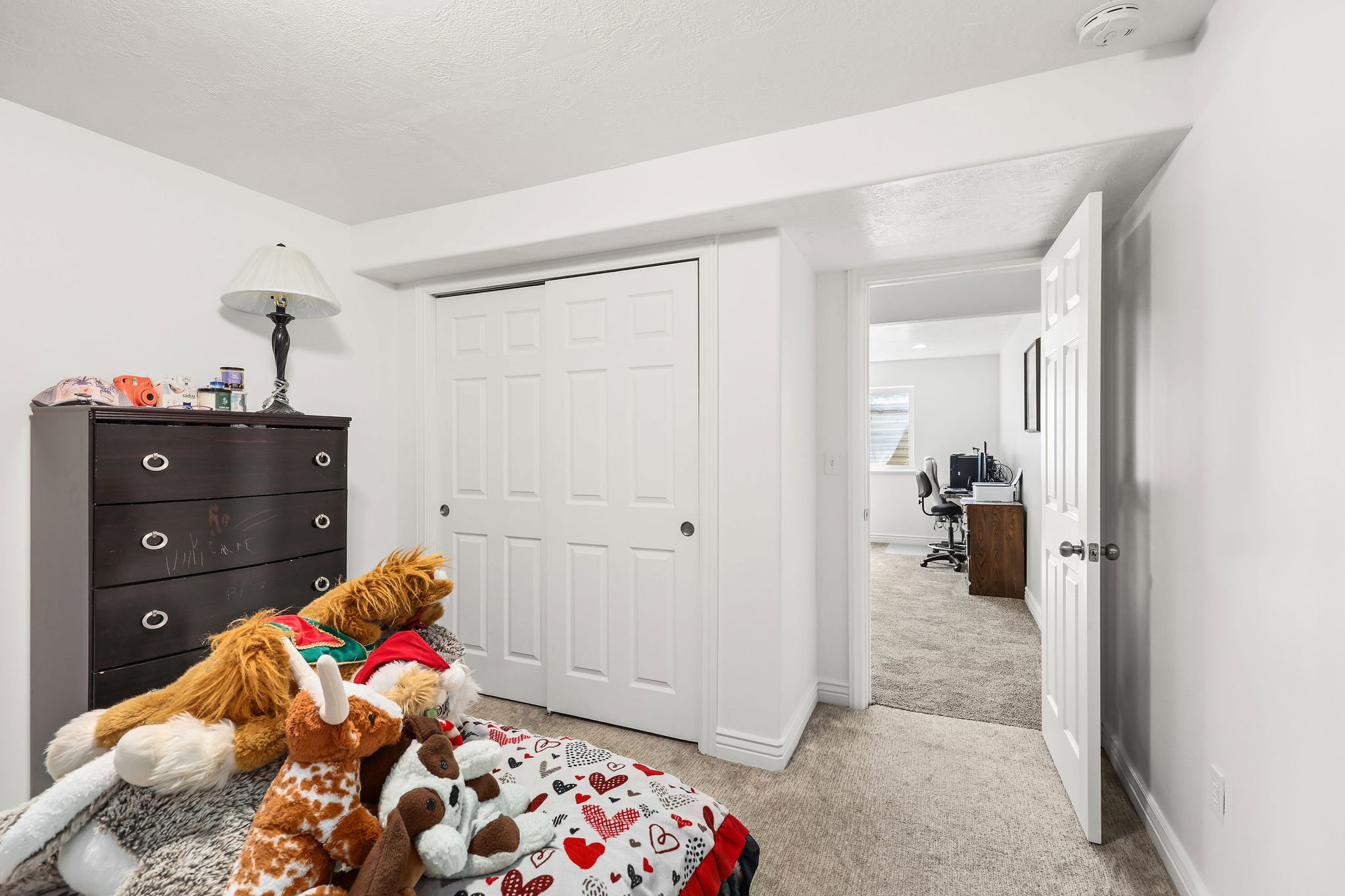 Carpeted interior room with white walls, a white bi-fold closet, and a doorway leading to another carpeted room